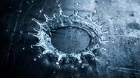 Water droplet splashing on surface creating dynamic crown-shaped splash with liquid spray, suitable for science, nature, and motion graphics projects.