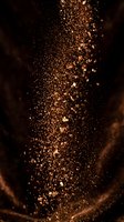 Golden glitter particles cascade and swirl against dark background, creating luxurious sparkle effect suitable for celebrations, cosmetics, and festive design projects.