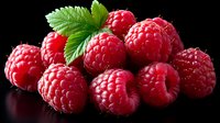 Fresh ripe raspberries with green mint leaf on black background, vibrant red berries for healthy eating, desserts, and food photography.