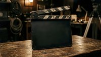 Blank film clapperboard on wooden table in professional production studio with cinema equipment and lighting in background, ready for movie or video project setup.