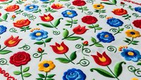 Colorful folk art floral embroidery pattern with roses, tulips and decorative swirls on white fabric background for traditional textile design projects.