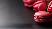 Pink raspberry macarons with fresh tulips on dark background, romantic food photography with selective focus and copy space for text.