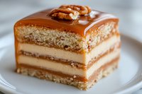 Layered caramel cake slice with vanilla cream filling, topped with salted caramel sauce and pecan nuts served on white plate, macro food photography.