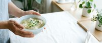 Person in light blue shirt holding bowl of fresh salad with greens and vegetables, healthy eating and nutrition concept for food blogs and wellness content.