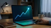 Young male professional analyzing upward trending financial graph on laptop screen in modern home office workspace with desk lamp and coffee mug.