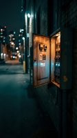 Illuminated electrical panel box on urban street at night with warm lighting and city bokeh background creating atmospheric industrial scene.