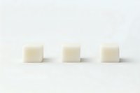 Three cream colored soap bars arranged in row on white background for natural skincare and beauty product photography.
