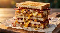 Grilled cheese sandwich with bacon and melted cheddar dripping down sides on rustic wooden board. Comfort food photography for restaurant menus and cooking blogs.
