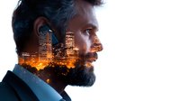 Bearded middle-aged Caucasian businessman in profile with creative double exposure effect showing illuminated city skyline at night merged with his silhouette, representing success.