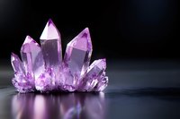 Purple amethyst crystal cluster with translucent points and facets on dark reflective surface, dramatic lighting highlights natural mineral formation structure.