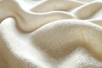 Natural linen fabric with soft waves and folds creating gentle shadows, close-up view showing detailed textile weave pattern and texture in beige tones.