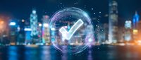 Digital checkmark symbol with glowing circular interface overlay on blurred city skyline at night. Business verification and approval concept.