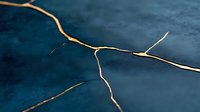Cracked surface with golden lines on dark blue textured background, representing kintsugi art technique and metaphor for healing and resilience in modern design.