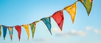 Colorful bunting flags strung across blue sky with white clouds, ideal for festive event decoration, party planning, and celebration design projects.