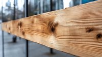 Diagonal wooden beam with natural grain pattern and knots in focus against blurred urban background, showcasing raw construction material texture.