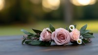 Elegant pink rose arrangement with eucalyptus leaves and white flowers on wooden surface with soft bokeh background for wedding decor.