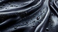 Water droplets on smooth black surface with flowing curves creating dramatic contrast and texture. Ideal for luxury product backgrounds.