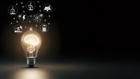Glowing light bulb with renewable energy icons on dark background representing sustainable electricity and green technology innovation concepts.
