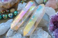 Iridescent rainbow aura quartz crystals with holographic surface reflecting prismatic colors among natural gemstone collection for healing and meditation.