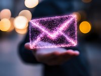 Glowing pink holographic envelope floating above palm with sparkle particles and bokeh lights in background, representing digital communication concept.