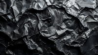 Dramatic black crumpled paper texture with deep shadows and highlights creating abstract organic patterns and folds, suitable for creative backgrounds.