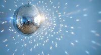 Shiny disco ball reflecting light spots across blue background creating party atmosphere for nightclub entertainment and celebration events.