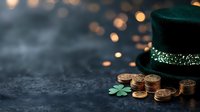 Magical St Patrick's Day composition with green leprechaun hat, golden coins and shamrock on dark background with bokeh lights, celebrating Irish holiday.