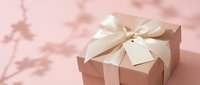 Elegant gift box with cream ribbon and blank tag on soft pink background with delicate floral shadows for special occasions and celebrations.