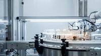Modern robotic arm conducting automated laboratory analysis with glass vials and test tubes in sterile white research facility for pharmaceutical testing.