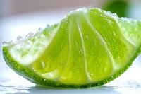 Fresh lime wedge with water droplets on bright surface, extreme macro shot showing juicy pulp and citrus texture in vibrant green color. Perfect for beverage and food designs.