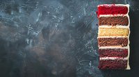 Colorful layered cake slice with red velvet, chocolate and vanilla layers on dark textured background with copy space for menu or recipe design.