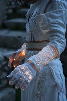 Futuristic glowing gloves with geometric patterns worn with white protective suit illuminate dark environment, creating sci-fi atmosphere for advanced technology concept.