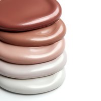 Stack of ceramic plates in warm earth tones from terracotta to cream, modern minimalist dinnerware set for kitchen and dining room decor.