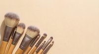 Professional makeup brush set with natural bristles arranged on neutral beige background for cosmetic application and beauty routine.