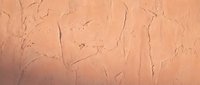 Cracked peach-colored plaster wall texture with natural weathering patterns and rough surface details for interior design backgrounds.