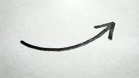 Upward trending arrow drawn on white paper surface, representing growth, success, and positive business momentum for financial concepts.