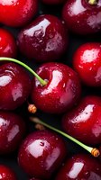Fresh ripe cherries with water drops on dark background, macro shot showing glossy red skin and green stems. Healthy organic summer fruit.