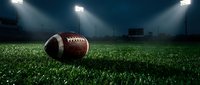 American football on green grass field under bright stadium lights at night for sports and game concepts.