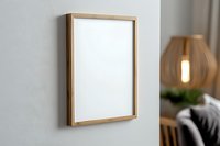Wooden frame mockup on white wall with modern interior decor, pendant lamp and furniture in background. Clean minimal home design presentation.