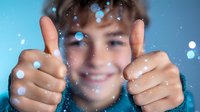 Cheerful Caucasian boy showing thumbs up with blue bokeh lights and sparkles in foreground, expressing positivity and success. Soft focus portrait.