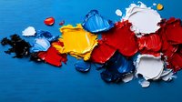 Vibrant oil paint smears in primary colors red, yellow, blue, white, and black against bright blue background, showcasing rich texture and artistic expression.