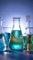 Laboratory glassware with colorful chemical solutions on blue background for scientific research and education.