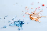 Contrasting blue and orange liquid drops scattered on white surface creating abstract artistic composition with splash effect and dynamic movement pattern.