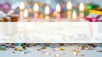 Festive celebration background with colorful confetti scattered on white wooden surface and warm bokeh lights creating magical party atmosphere.