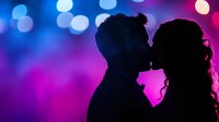 Romantic silhouette of couple kissing against vibrant purple and blue bokeh lights background, creating dreamy atmosphere for wedding and Valentine designs.