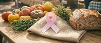 Fresh organic produce and whole grain bread arranged on burlap with pink awareness ribbon symbolizing health, nutrition, and wellness support for disease prevention campaigns.