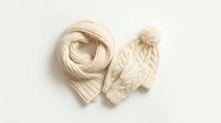 Cozy beige knitted winter scarf and matching pom pom hat set isolated on neutral background for seasonal fashion and warmth accessories design.