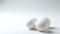 Fresh white chicken eggs on clean white background with soft shadows, minimalist food photography for cooking and nutrition concepts.