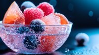 Fresh mixed berries and citrus fruits covered in sparkling water droplets in glass bowl against dark background, creating refreshing summer drink composition.