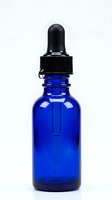 Cobalt glass dropper bottle with black pipette cap isolated on white background, suitable for essential oils, serums, tinctures, and cosmetic packaging design.